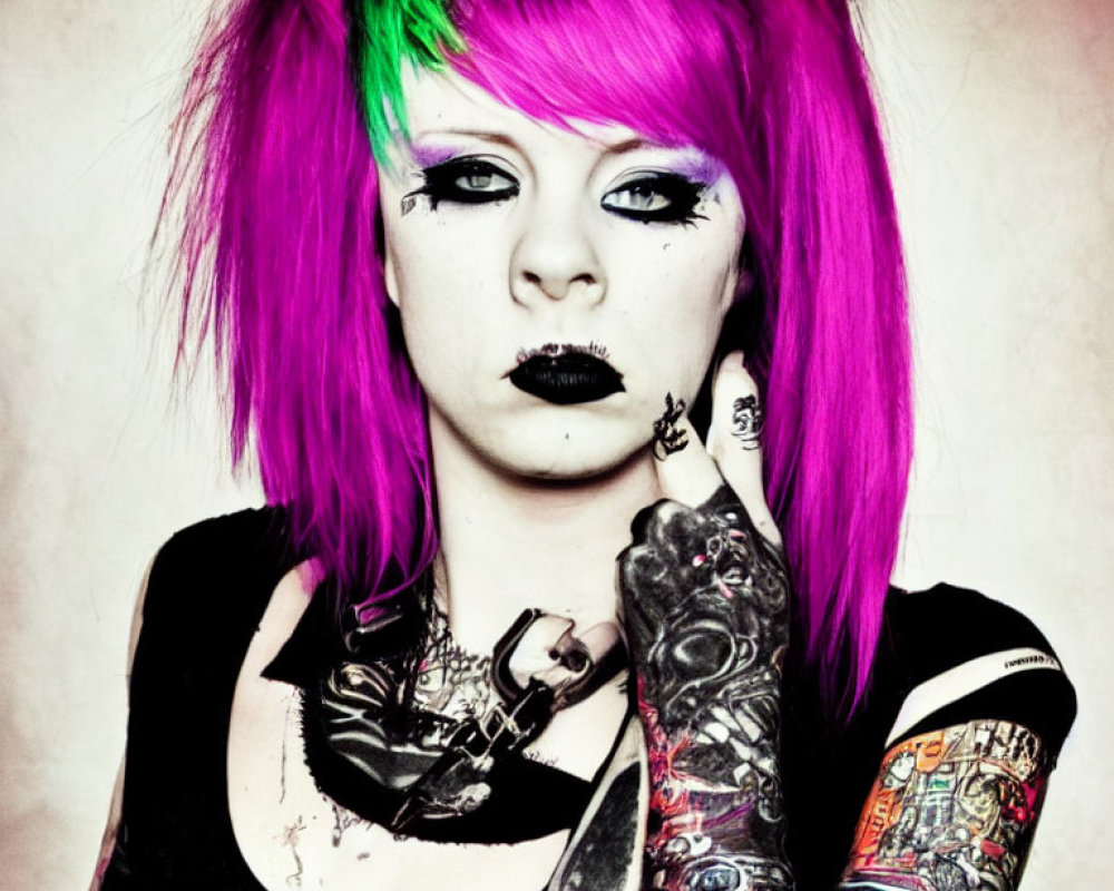 Vibrant pink and green hair, black lipstick, heavily tattooed arms pose in punk/goth