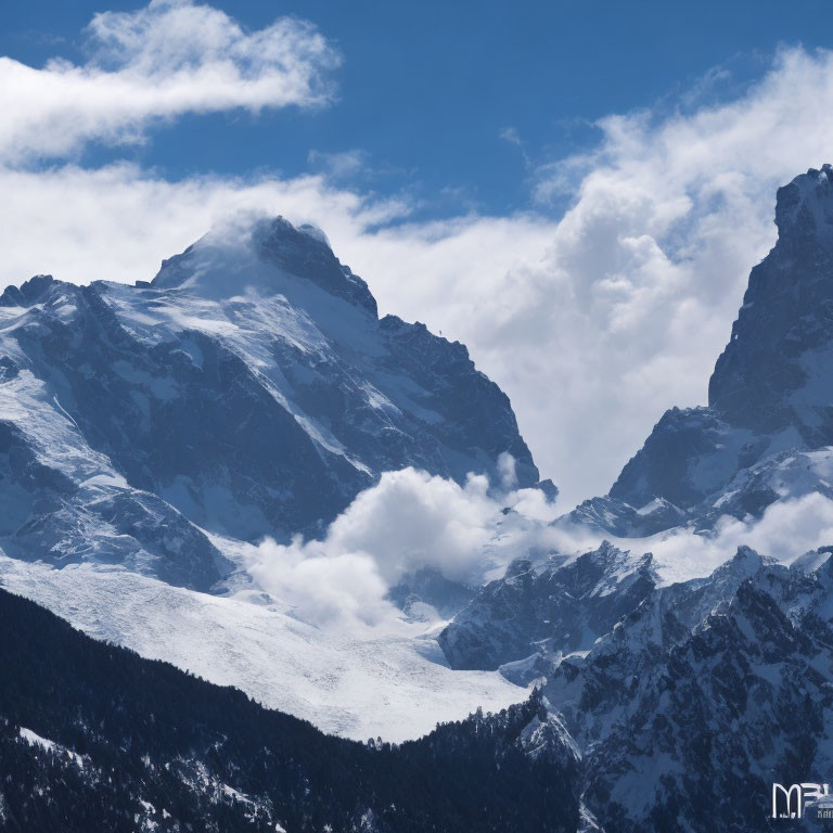 Snow-covered mountain peaks with midsection clouds in clear blue sky