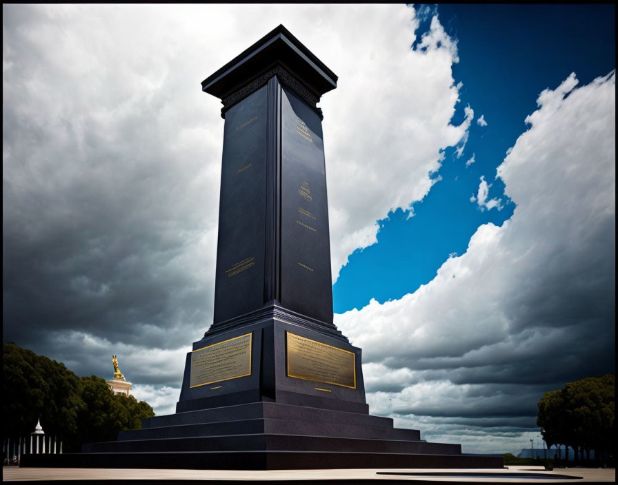 Tall Dark Obelisk with Gold Plaques Against Dramatic Sky