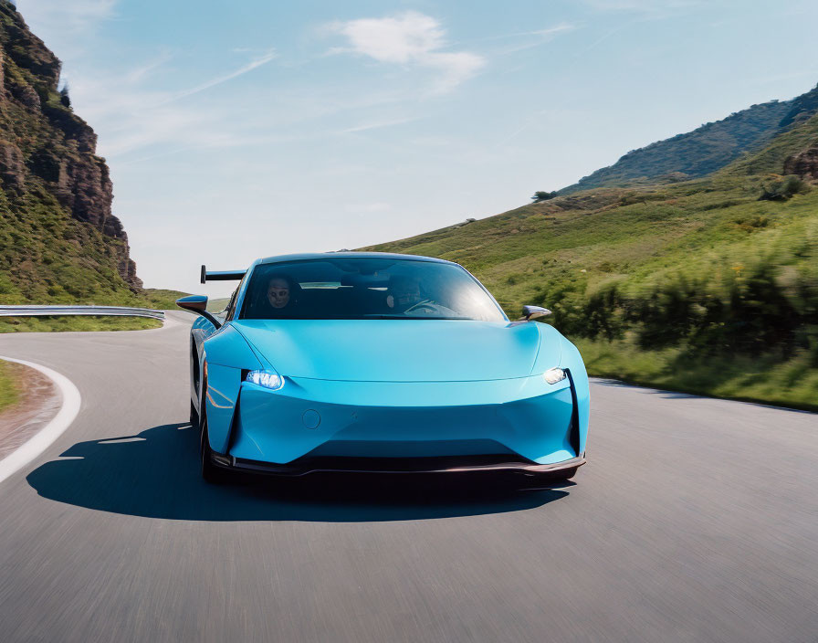 Blue sports car with rear wing on mountain road under clear sky