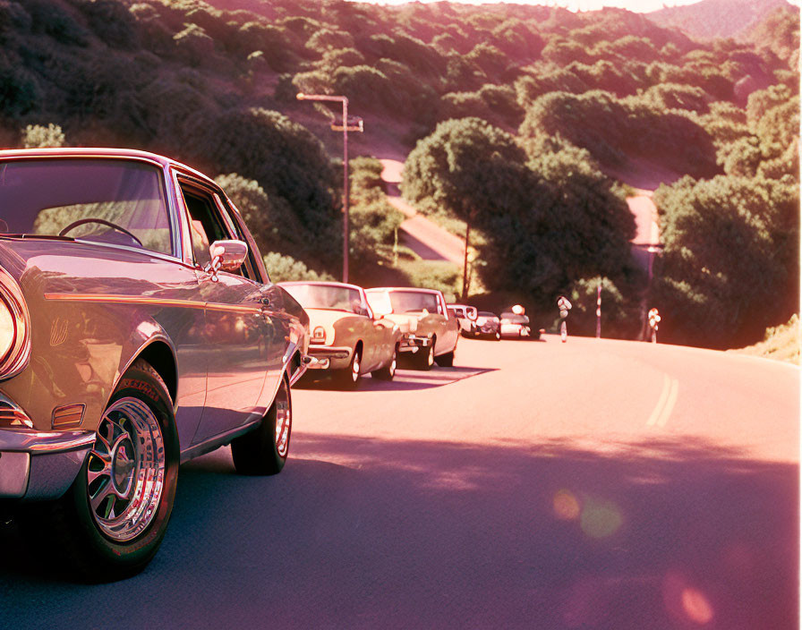 Classic Cars Driving on Scenic Winding Road at Sunset