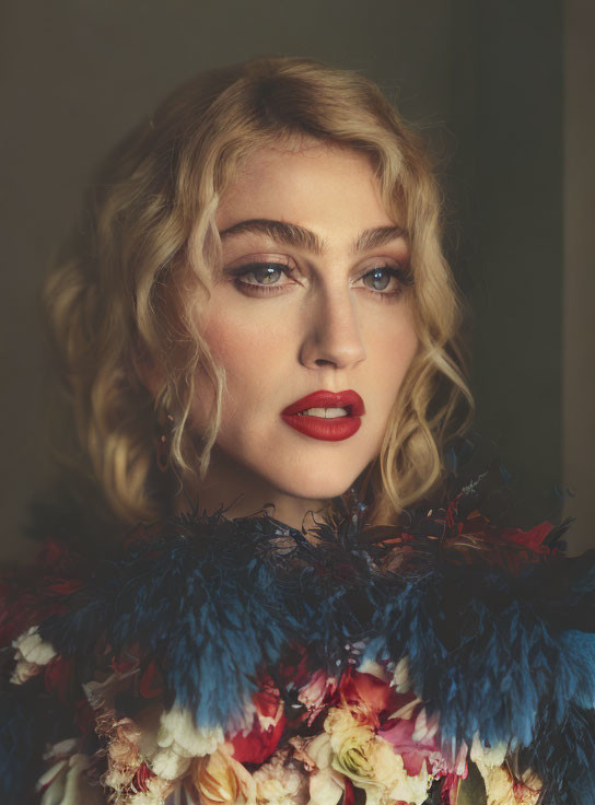 Person with Curly Blonde Hair and Red Lipstick in Vibrant Feathered Garment