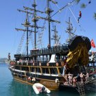 Pirate ship with skull sails on calm sea among other ships