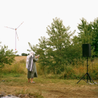 Couple in grassy field with wind turbines under overcast sky