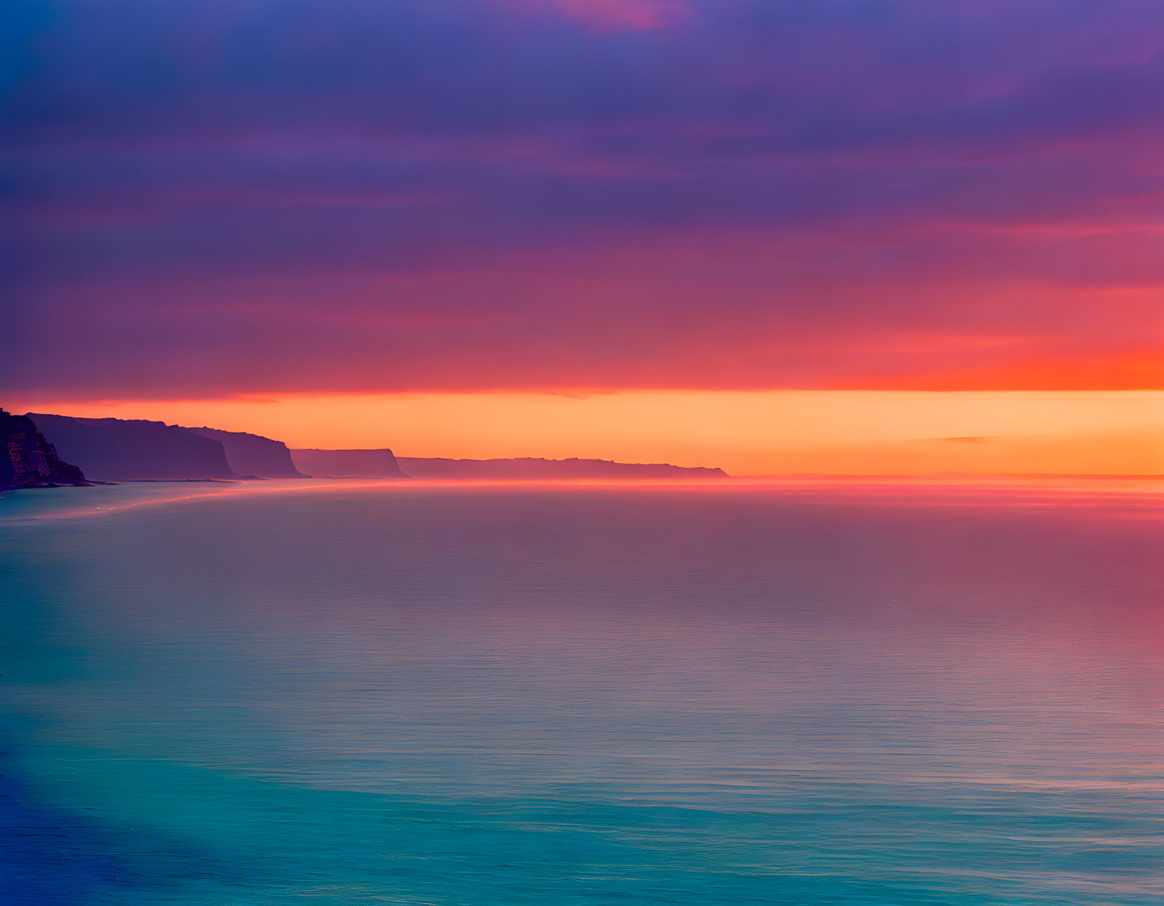 Tranquil seascape at sunset with vibrant purple, pink, and blue hues