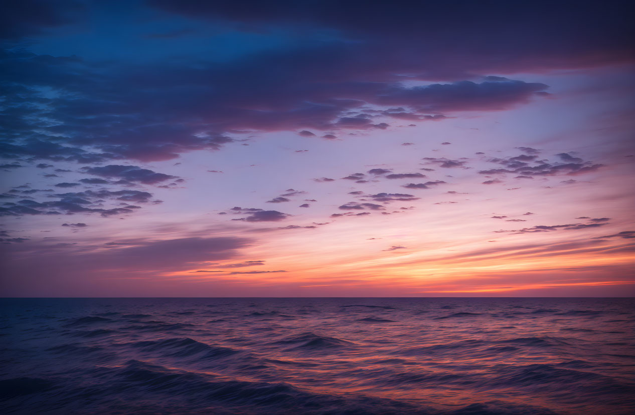 Vibrant pink, purple, and blue sunset over ocean waves