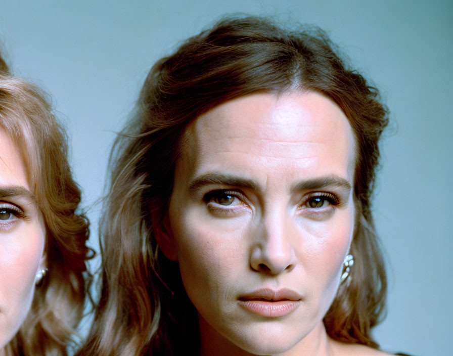 Intense close-up of two women, one focused with dark eyes, the other's half-face blurred