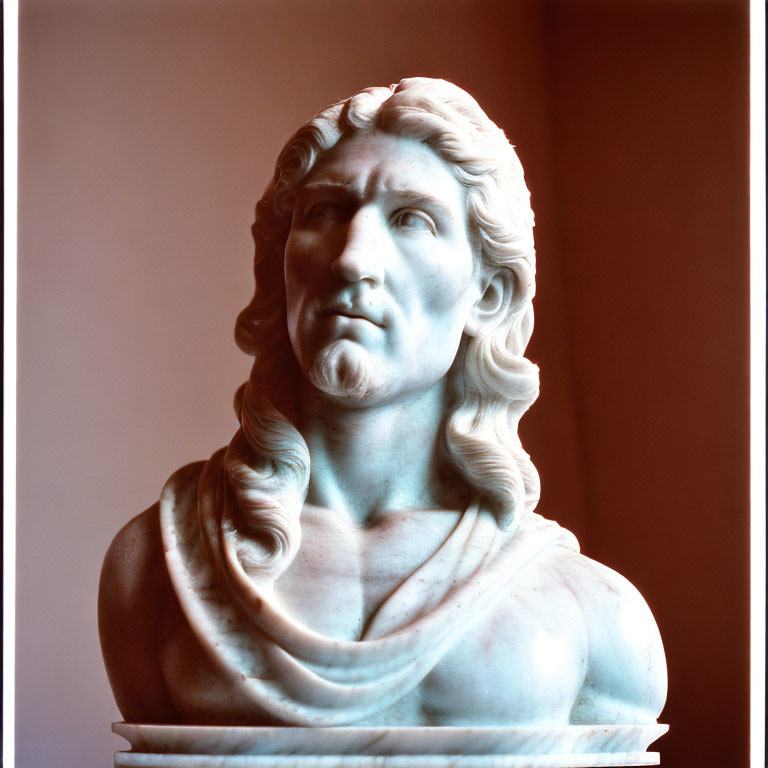 Marble bust of a man with long hair on soft pink background