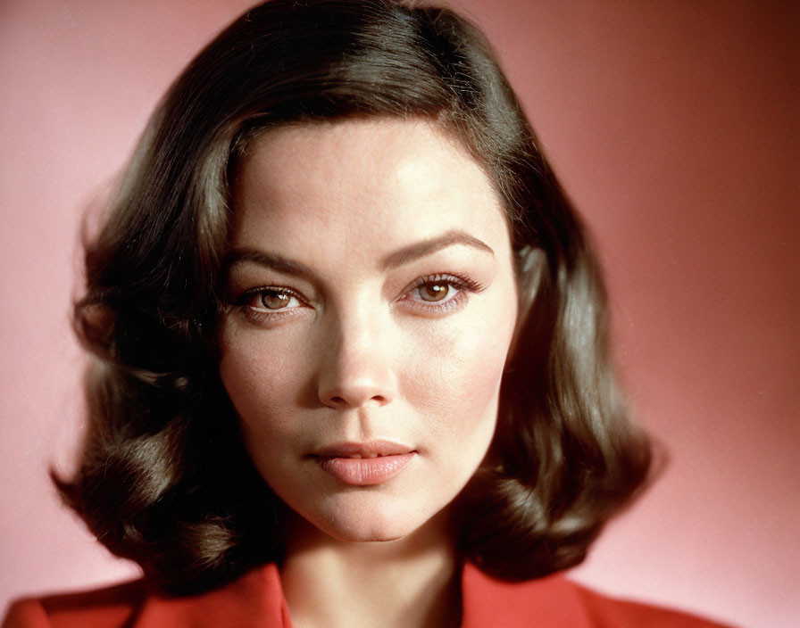 Portrait of woman with short wavy hair, subtle makeup, red outfit, pink backdrop