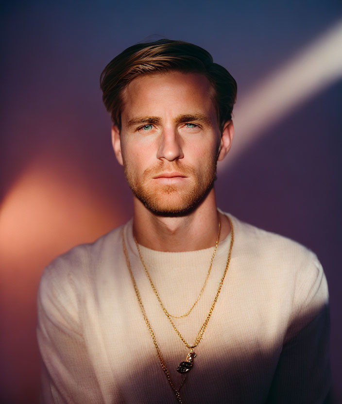 Blond Man in Cream Sweater with Blue Eyes and Necklaces