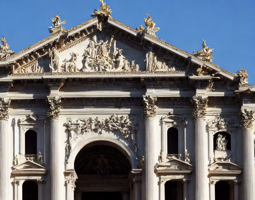 Baroque facade with Corinthian columns and sculptures under clear blue sky