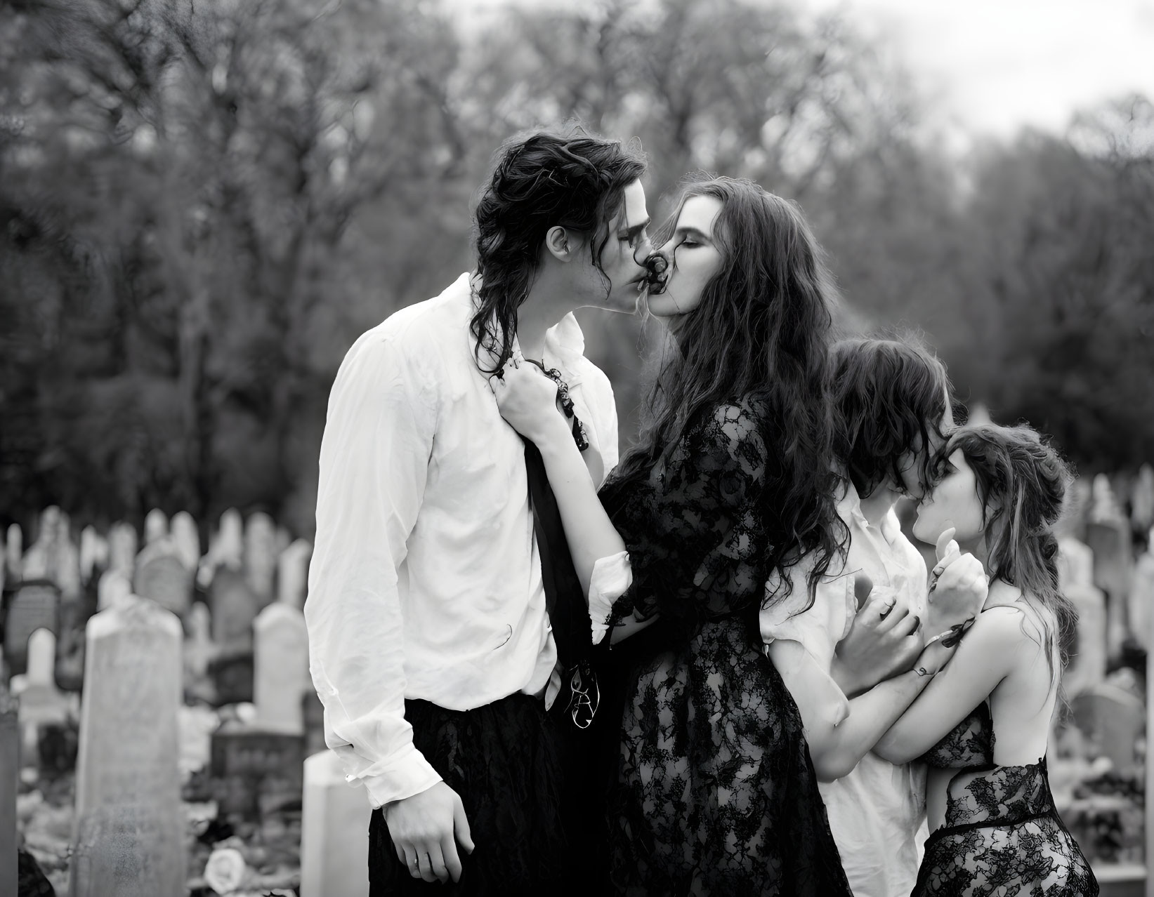 Gothic couple kissing in cemetery with children among gravestones