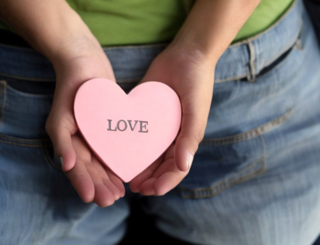 Pink heart-shaped object with "LOVE" against torso