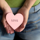 Pink heart-shaped object with "LOVE" against torso