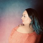 Teal-Tinted Hair Woman in Orange Top on Textured Pink and Blue Background