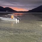 Wooden boat with lute design on wavy water under surreal sky with multiple moons and glowing orb