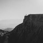 Teapot-shaped building with cup roof on cliff overlooking misty mountains