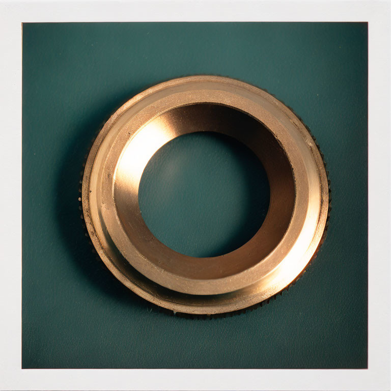 Circular Gold Metal Ring on Teal Background with Soft Shadow