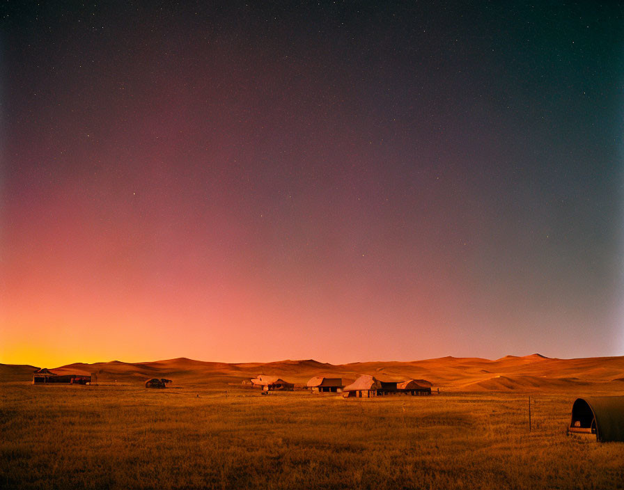 Rural landscape at night with starry sky & warm glow