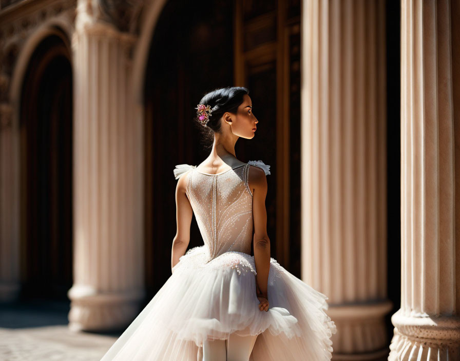 Woman in white ballet tutu near columns with flower in hair