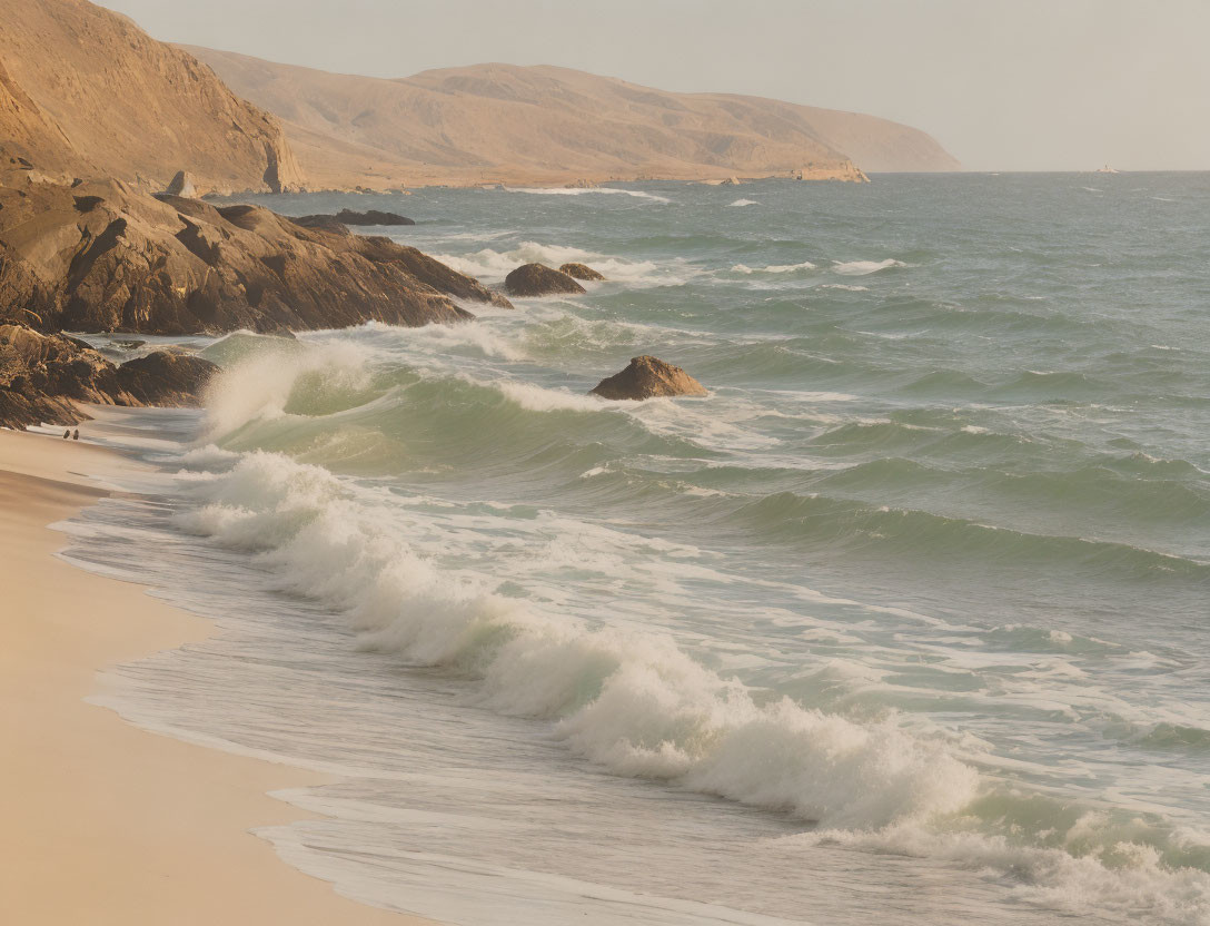 Tranquil beach scene with gentle waves, rugged cliffs, and hazy sky