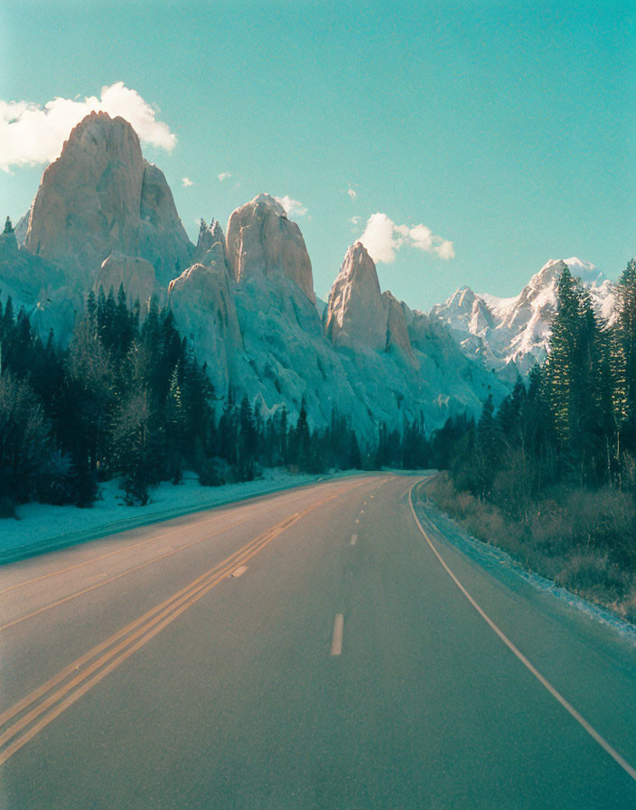 Scenic road with towering rocky mountains and evergreen trees