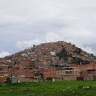 Terracotta terraced structure with grass and plane under cloudy sky