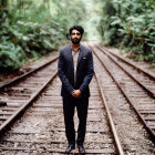 Smiling man in dark suit on forest railway track