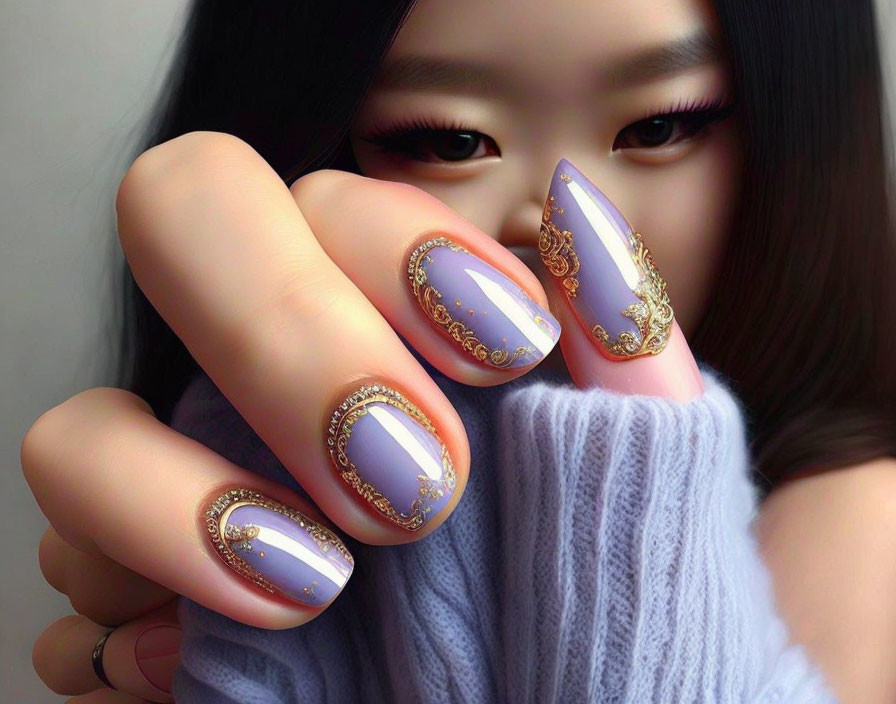 Detailed purple and gold almond-shaped nails on hand.