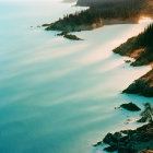 Sailboat on serene coastline with misty cliffs under warm light