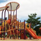 Vibrant playground with slides, climbing structures, and ladders under cloudy skies