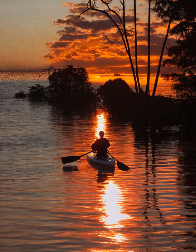 Kayaker on Calm Water at Vibrant Sunset with Orange Tones