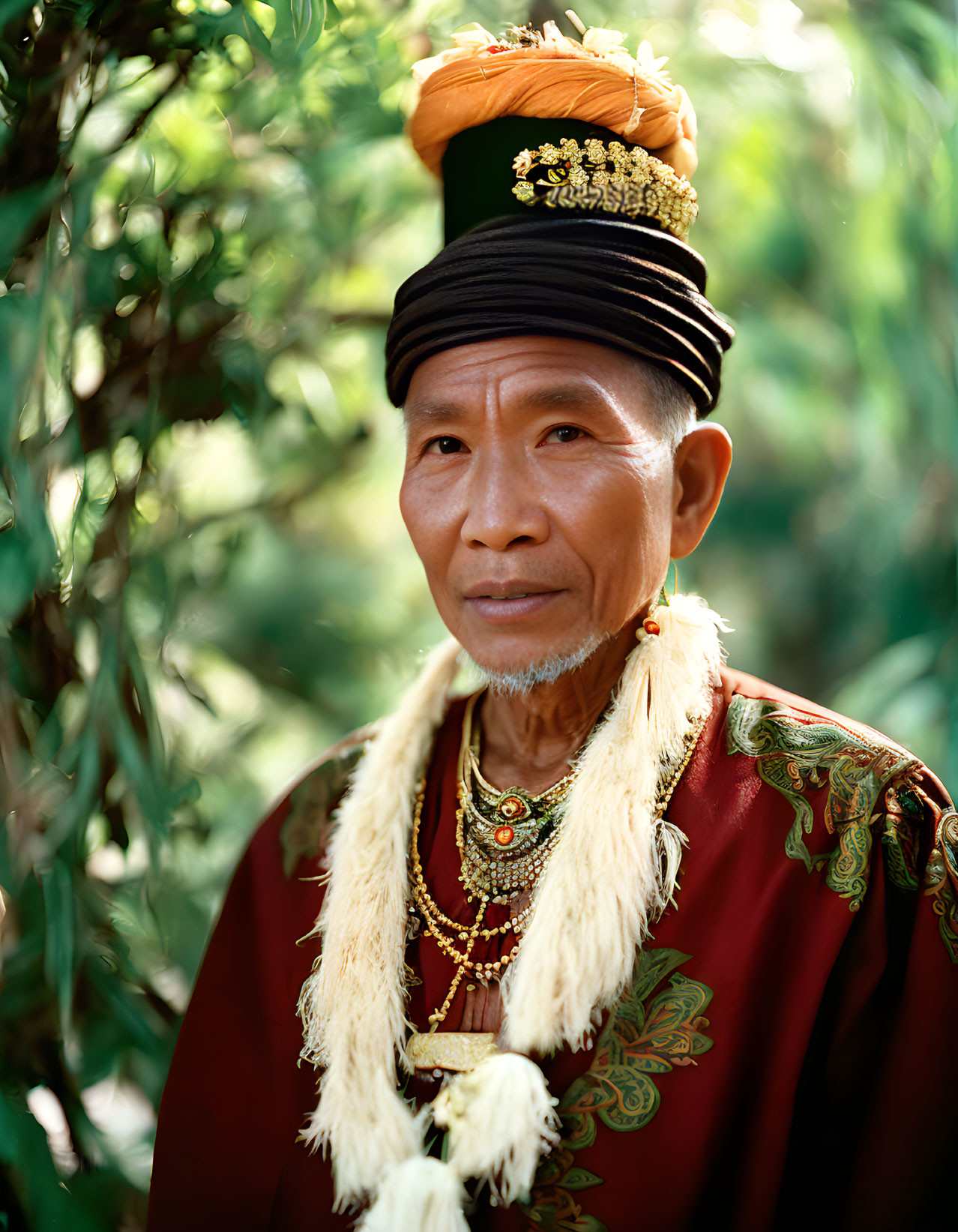 Elder man in traditional attire with ornate headdress and necklace