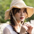 Digital artwork: Young woman with braided hair in wide-brimmed hat and vintage dress among d