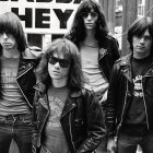 Vintage black and white photo of people in retro rock style with leather jackets and sunglasses in front of graffiti