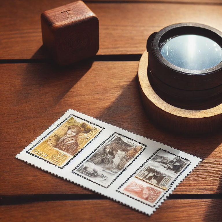 Vintage postage stamps with magnifying glass on wooden surface