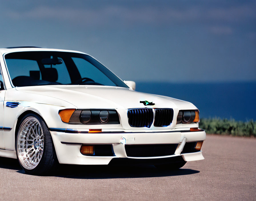 Vintage White BMW Car with Kidney Grilles and Pop-Up Headlights on Asphalt Road