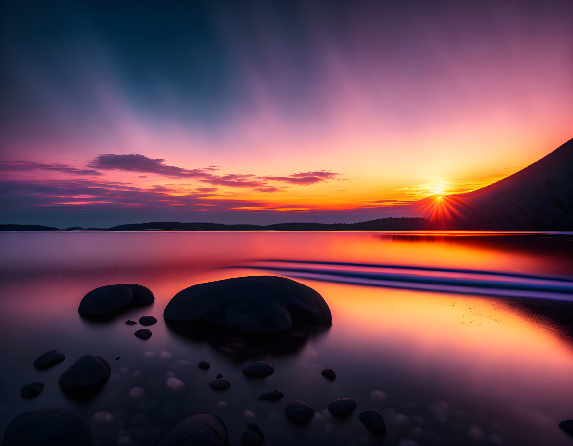 Scenic sunset over calm lake with smooth stones and vibrant purple and orange sky