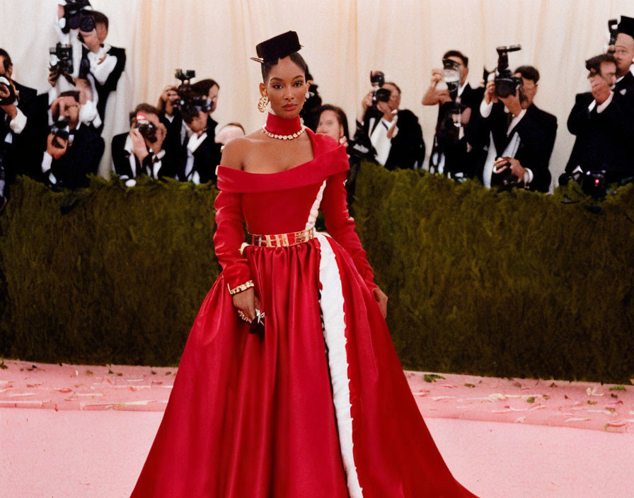 Elegant woman in red off-the-shoulder gown on pink carpet