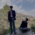 Stylish Young Men Posing on Rock with Mountain Backdrop