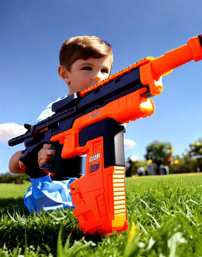 Young child playing with orange and blue toy blaster in grassy field