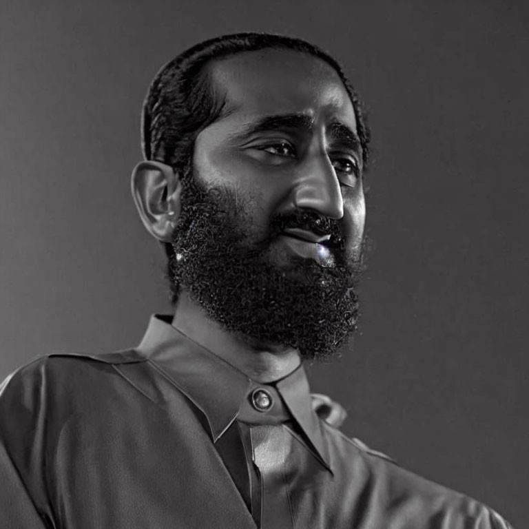 Monochrome portrait of a bearded man in collared shirt, looking away.