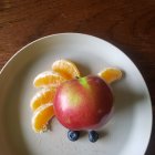 Whimsical sea creature dessert with citrus slices, herbs, and toy dinosaur on wooden table