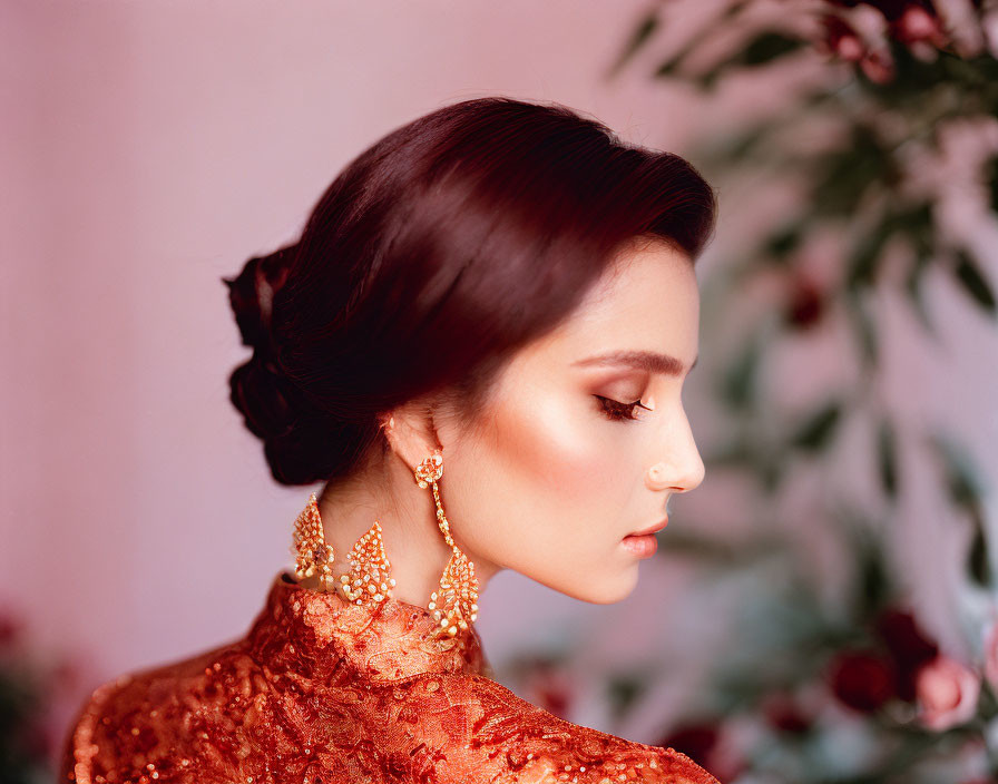 Woman with Elegant Updo, Gold Earrings, Red Lace Dress on Pink Backdrop