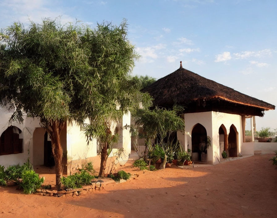 Traditional Thatched-Roof House Surrounded by Greenery at Dusk