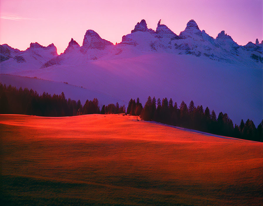 Vibrant pink Alpenglow on mountain peaks at twilight