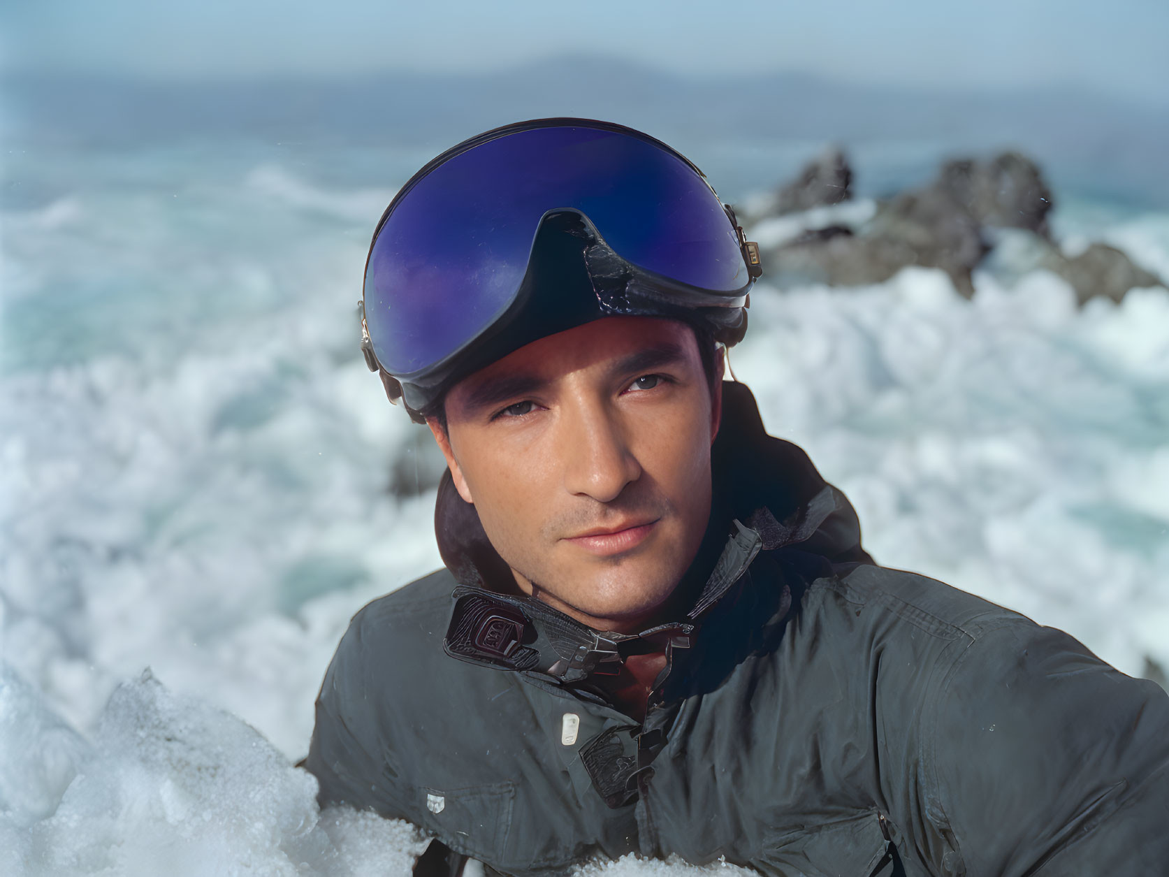 Man in ski goggles and jacket in snowy landscape