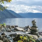 Tranquil landscape with waterfalls, pine trees, mountains, and lake