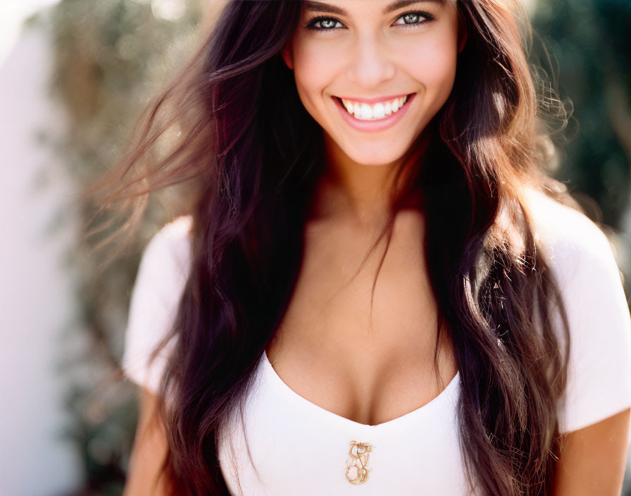 Smiling woman with long dark hair in white top outdoors