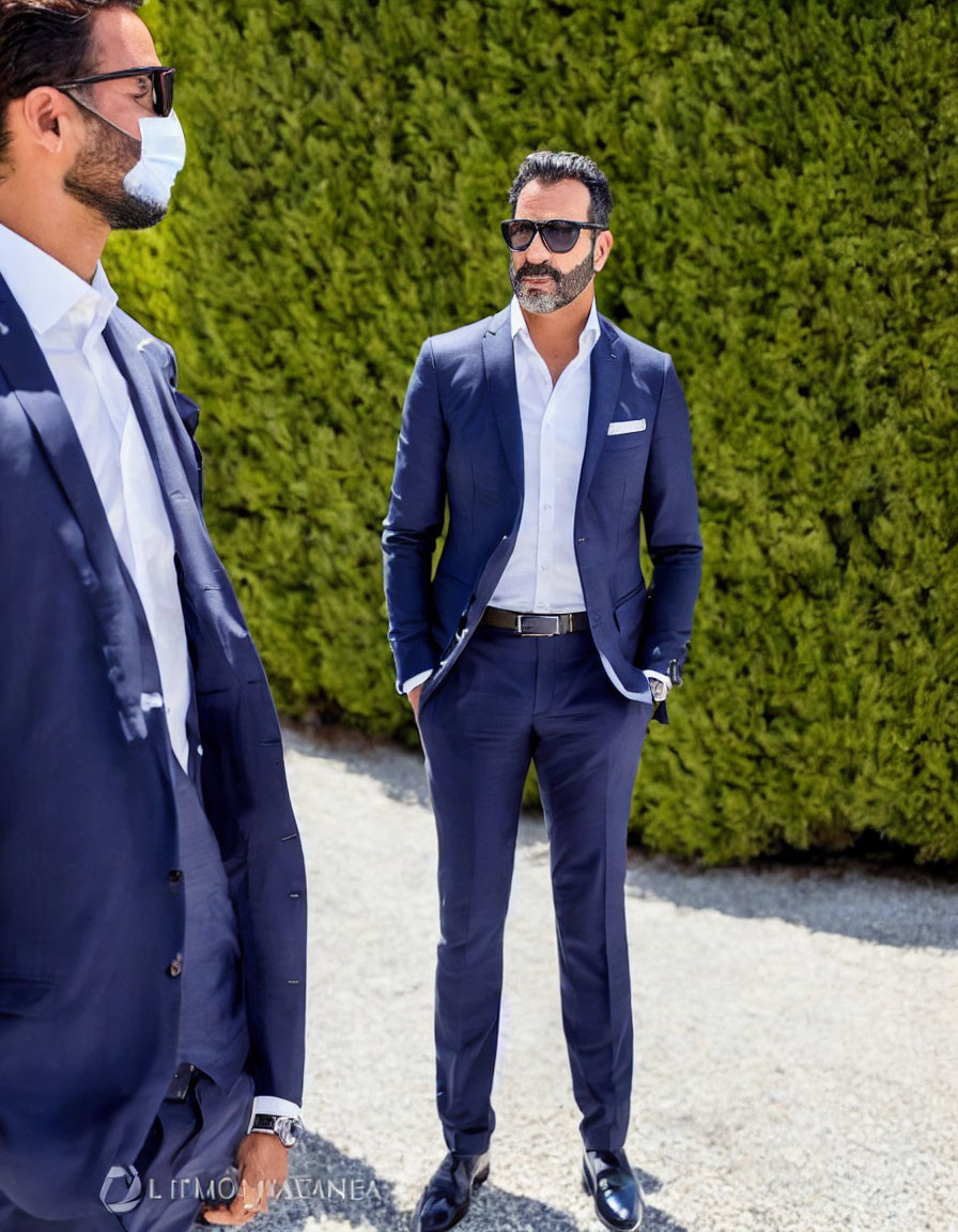 Confident man in navy suit with sunglasses next to man in face mask